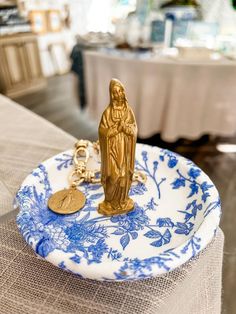 a blue and white plate with a gold figurine sitting on top of it