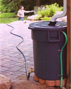 a black trash can sitting next to a brick walkway