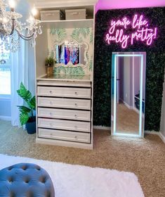 a room with a mirror, dresser and lights on the wall next to a bed