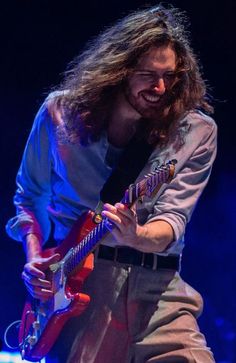 a man with long hair playing an electric guitar