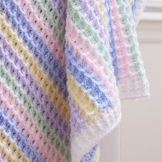 a multicolored crocheted blanket draped over a window sill