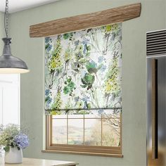 a kitchen with green walls and a window covered in floral fabric next to a refrigerator