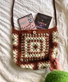 a crocheted purse sitting on top of a bed next to a handbag