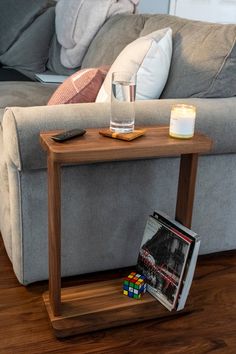 a coffee table with a magazine and candle on it next to a couch in a living room