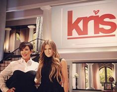 two women standing next to each other in front of a kris sign