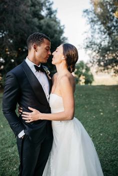 a bride and groom are standing in the grass