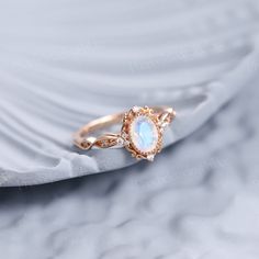 a gold ring with an opal stone in the center on top of a white cloth