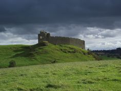 an old castle sitting on top of a lush green hillside