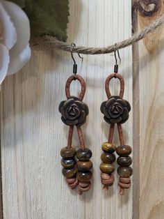 two brown and black beads are hanging from a string on a wooden surface next to a flower