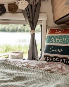 a bed sitting next to a window in a bedroom under a blanket on top of a bed