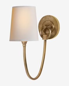 a wall light with a white shade on the side and a gold finish to it