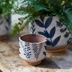 two planters sitting on top of a wooden table next to each other with plants in them