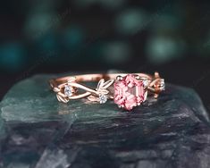 a close up view of a pink ring on top of a rock with some diamonds