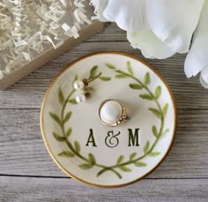 a wedding ring sits on a plate next to flowers and a box with the initials