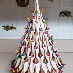 a white and brown christmas tree with multicolored lights on it's top