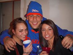 two women and a man posing for the camera with cups in front of their faces