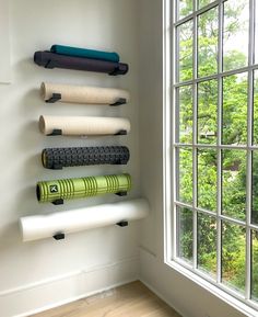 there are many yoga mats lined up on the wall next to each other in front of a window