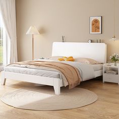 a white bed sitting on top of a hard wood floor next to a table and lamp