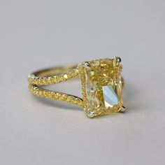 a fancy yellow diamond ring on a white background with gold accents and diamonds around the band