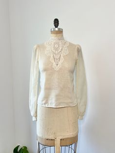 1970s Gunne Sax sheer cotton ivory long sleeve blouse with button down closure down the back middle. This shirt has a gorgeous floral lace mock neck that continues down the front middle.  In very good vintage condition, minor discoloration by armpit it hardly noticeable! B: 34" W: 31" L: 22" Vintage Cream Blouse, Vintage White Blouse For Spring, Vintage Beige Blouse For Fall, Vintage Beige Blouse With Lace Collar, Vintage Beige Cotton Blouse, Vintage Cream Tops For Daywear, Vintage Long Sleeve Tops For Daywear, 1970s Long Sleeve Blouse, Vintage Long Sleeve Blouse In Vintage White