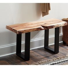 a wooden bench sitting on top of a hard wood floor next to a pair of boots