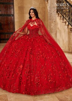 a woman in a red ball gown with a veil on her head, standing next to stairs