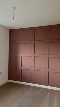 an empty room with red walls and carpeted flooring in the foreground, there is a radiator on the far wall