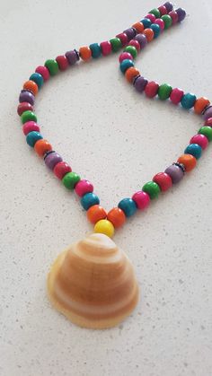 A handcrafted necklace featuring natural sea shells and a variety of colorful beads. An ideal gift for any occasion, it pairs well with any outfit. Necklace Shell, Wooden Bead Necklaces, Beach Necklace, Beach Necklaces, Rainbow Necklace, Seashell Necklace, Summer Necklace, Shell Necklace, Handcrafted Necklace