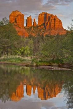 the red rocks are reflected in the still water