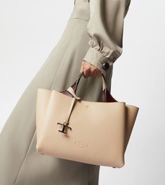 Bag in soft exposed grain leather, with Tod's logo stamped on the front, flat handles and removable shoulder strap. The interior comes with three compartments separated by zipped central pockets. An elegant creation enhanced by distinctive iconic detailing, such as the metal T Timeless pendant and T-stitching. Timeless Beige Calf Leather Bag, Tan Pebbled Leather Top Handle Bag, Designer Pebbled Leather Bag With Double Handles, Cream Calf Leather Bag For Everyday Use, Beige Calf Leather Bag With Dust Bag, Everyday Cream Calf Leather Bag, Designer Double Handle Pebbled Leather Bag, Cream Calf Leather Bag With Soft Leather, Beige Calf Leather Tote Bag