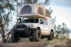 an off road vehicle with a tent on the roof and four wheels attached to it