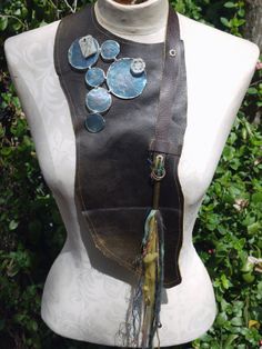 a white mannequin with a brown leather purse on it's back and blue glass buttons