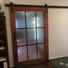 an empty room with a glass door and bookcases on the floor, in front of a white wall