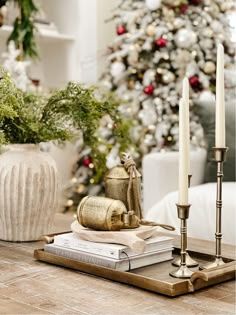 a christmas tree is in the background with candles, books and other decorations on a table