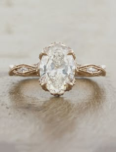 an oval shaped diamond ring with twisted band and center stone in the middle, set on top of a wooden surface