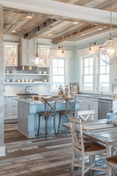 a kitchen with white cabinets and wooden floors, along with an island in the middle