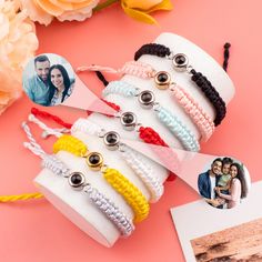 several bracelets with pictures on them are sitting next to some flowers and an envelope