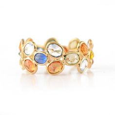 a yellow gold ring with multi colored stones