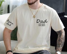 a man sitting on top of a couch wearing a shirt that says dad est 2020