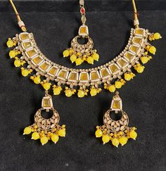 Make a statement with this exquisite jewellery set from Harkirt trade. The beautifully crafted round neck necklace set features stunning stone work in a gold colour. Made in India, this piece is a true reflection of fine craftsmanship and attention to detail. Perfect for any occasion, this jewellery set will elevate any outfit and add a touch of glamour to your look. Ideal for those who appreciate quality and sophistication, this necklace set is a must-have addition to any jewellery collection. Bollywood Style Round Necklaces With Stone Work, Kundan Chandbali Jewelry With Stones, Festive Kundan Jewelry With Stones, Heavy Round Bollywood Necklaces, Heavy Round Bollywood Style Necklace, Traditional Jewelry With Stones For Festivals, Gold Jewelry With Mirror Work For Gift, Festive Necklaces With Stone Setting, Temple Jewelry Chandbali With Stones