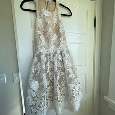 a white dress hanging on a hanger in front of a door with an iron hook