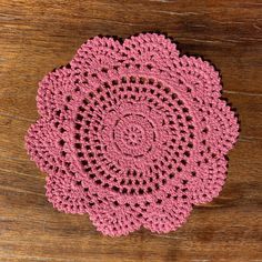 a crocheted doily sits on a wooden surface