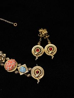 "Very little information can be found on the PIK MGK NYC jewelry makers but they did produce an exceptional art glass and serpent slide bracelet and earrings with this set; the dangle screw back earrings features the curled serpent and ruby red stone which matches one of the link on the bracelet and are 2\" long; the bracelet is 7\" long and 3/4\" wide with spring safety chain; each of the nine embossed links feature a different design and stone; the stone colors are amazing; ruby red, speckled Formal Metal Clip-on Jewelry, Fine Jewelry Bracelet With Cabochon, Art Deco Dangle Pierced Earrings, Victorian Jewelry With Matching Dangle Earrings, Victorian Dangle Jewelry With Matching Earrings, Victorian Style Metal Clip-on Jewelry, Collectible Metal Drop Earrings, Art Deco Clip-on Jewelry For Formal Occasions, Clip-on Art Deco Jewelry For Formal Occasions