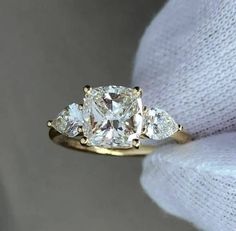 three stone diamond ring on top of a white cloth with two diamonds in the middle