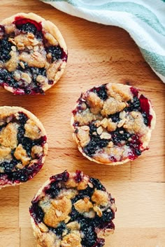 four blueberry crumbles sitting on top of a wooden cutting board