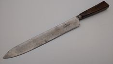 a large knife with a wooden handle on a white surface