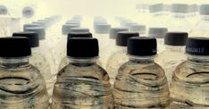 four bottled water bottles are lined up in a row with black caps on the lids