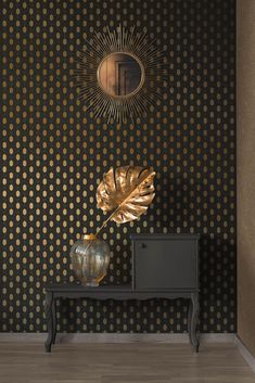 a black table with a gold leaf on it in front of a polka dot wallpaper