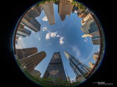 looking up at skyscrapers from the ground in a circular view with blue sky and clouds