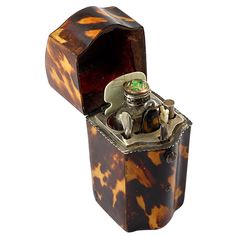 an old fashioned lighter with a green light on top is sitting in a case that looks like it has been made out of tortoiseshells